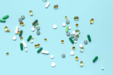 Balık yağı kapsülleri ve mavi arka planda farklı haplar.