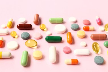 Balık yağı kapsülleri ve pembe arka planda farklı haplar.