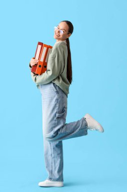 Mavi arkaplanda belge klasörleri olan genç bir kadın