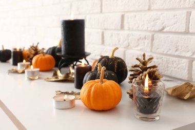 Beyaz tuğla duvarın yanında balkabakları, koniler ve mumlar