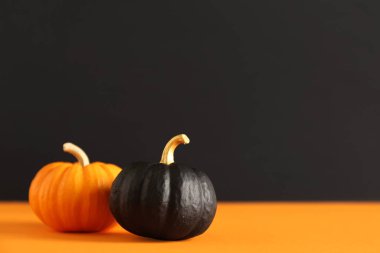 Siyah duvarın yanındaki turuncu masaya boyanmış balkabakları.