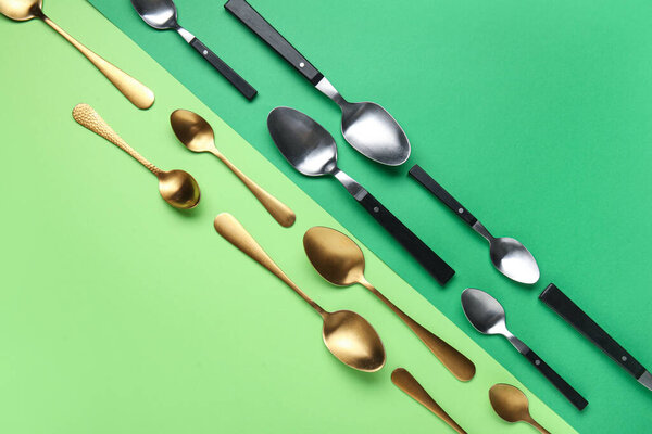 Different stylish spoons on color background