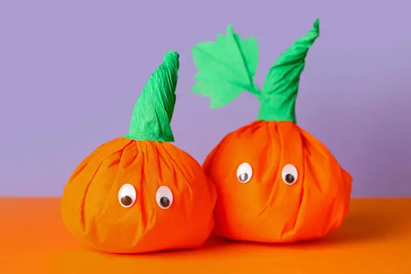 Paper pumpkins for Halloween on color background, closeup