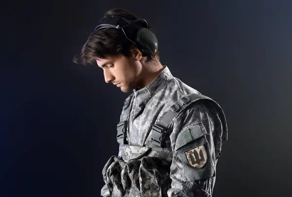Young male soldier with tactical headset on black background