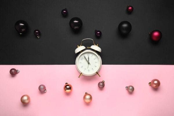 Alarm clock with Christmas balls on colorful background