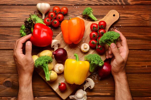 Man with different fresh vegetables on wooden background