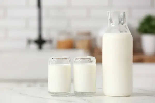 Glasses and bottle of fresh milk on white table