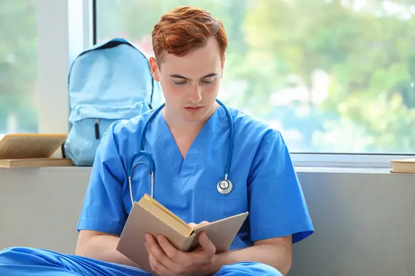 Male medical student reading book at university