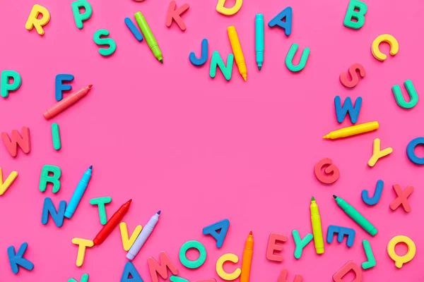 Frame made of colorful letters and markers on pink background