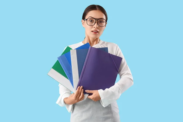 Young Asian businesswoman with document folders on blue background