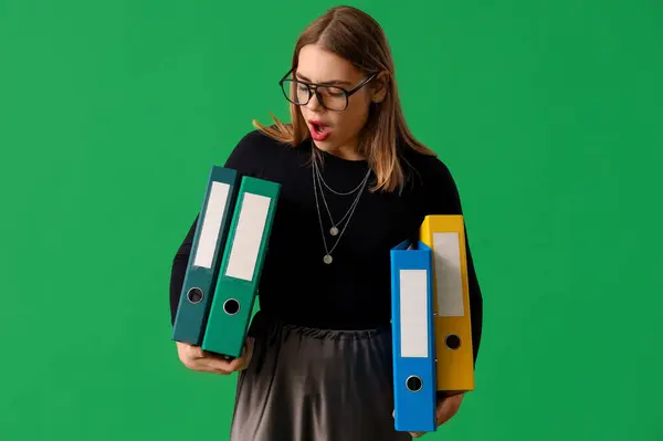 Stressed businesswoman with document folders on green background