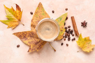 Renkli arka planda bir fincan aromatik kahve, fasulye ve düşmüş yapraklı kompozisyon