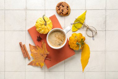 Hafif fayans zemininde aromatik kahve, kitap ve sonbahar dekoru içeren kompozisyon