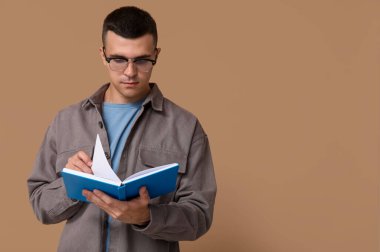 Bej arkaplan kitabı okuyan yakışıklı genç adam.