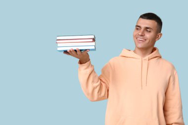 Mavi arka plan kitapları olan yakışıklı bir genç.