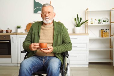 Evde bir fincan kahveyle tekerlekli sandalyedeki son sınıf öğrencisi.