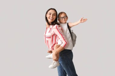 Güzel anne ve küçük tatlı kızı gri arka planda birlikte eğleniyorlar.