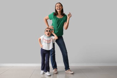 Gri duvarın yanında küçük tatlı kızı olan güzel bir anne.