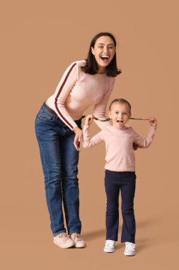 Güzel anne ve küçük tatlı kızı kahverengi arka planda birlikte eğleniyorlar.