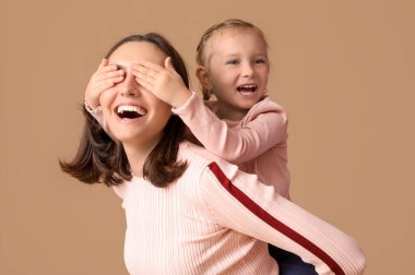 Güzel anne ve küçük tatlı kızı kahverengi arka planda birlikte eğleniyorlar.