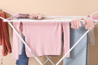 Bej arka planda kışlık giysileri olan kurutucu.