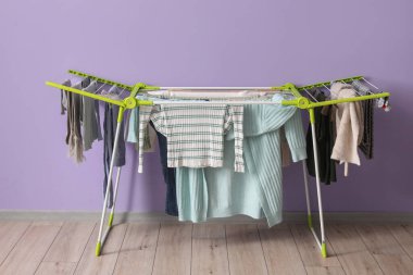 Kışlık giysileri olan kurutucu mor duvarın yanında.