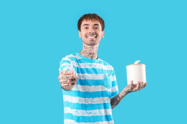 Mavi arka planda burun damlası ve dokuları olan alerjik genç bir adam.