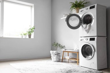 Çamaşır makinesi ve gri banklı modern çamaşır odasının içi.
