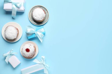 Mavi zemin üzerinde donutlar ve hediye kutuları olan Hanuka kompozisyonu