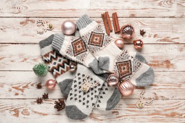 Noel süsleriyle örülmüş çoraplar ve beyaz ahşap arka planda farklı baharatlar.