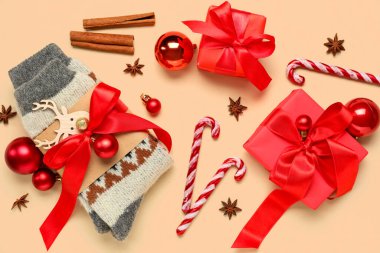 Noel süsleriyle örülmüş çoraplar, farklı baharatlar ve bej arka planda hediye kutuları.