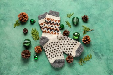 Kozalaklı çoraplar, yeşil arka planda Noel topları ve koniler.