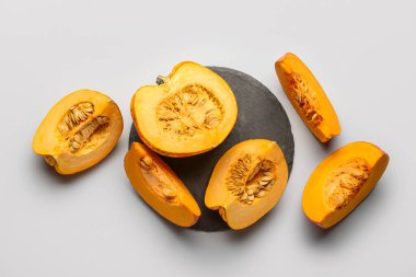 Gri arka planda kesilmiş taze balkabakları olan siyah tahta.