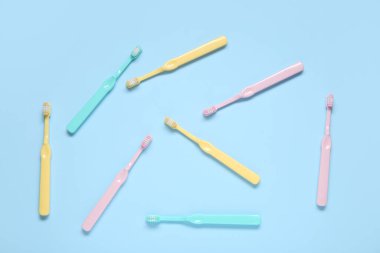 Mavi arka plan üzerinde renkli diş fırçaları.