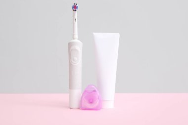 Arka planda diş macunu ve diş ipiyle elektrikli diş fırçası..