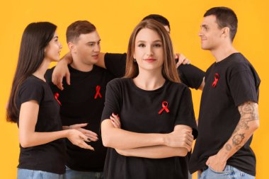 Sarı arka planda kırmızı kurdeleli bir grup genç. Dünya AIDS Günü konsepti