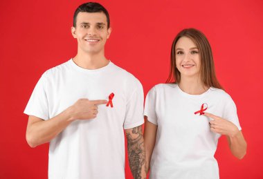 Arka planda kırmızı kurdeleli genç bir adam ve kadın. Dünya AIDS Günü konsepti