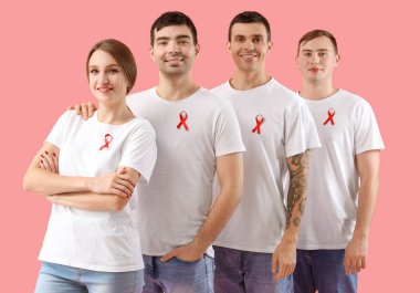 Pembe arka planda kırmızı kurdeleli bir grup genç. Dünya AIDS Günü konsepti