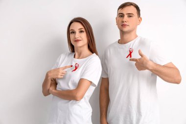 Beyaz arka planda kırmızı kurdeleli genç bir adam ve bir kadın. Dünya AIDS Günü konsepti