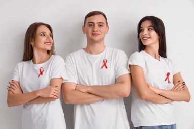 Beyaz arka planda kırmızı kurdeleli bir grup genç. Dünya AIDS Günü konsepti
