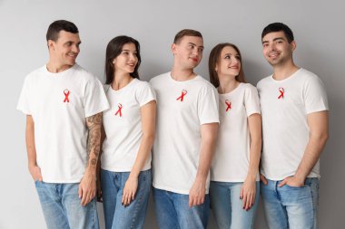 Gri arka planda kırmızı kurdeleli bir grup genç. Dünya AIDS Günü konsepti