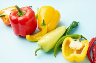 Mavi arka planda farklı taze biberler.