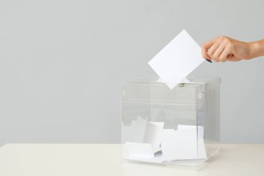 El, oy pusulasına gri arka planda oy kağıdı koyuyor