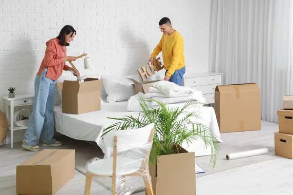 Happy young couple packing things in bedroom on moving day