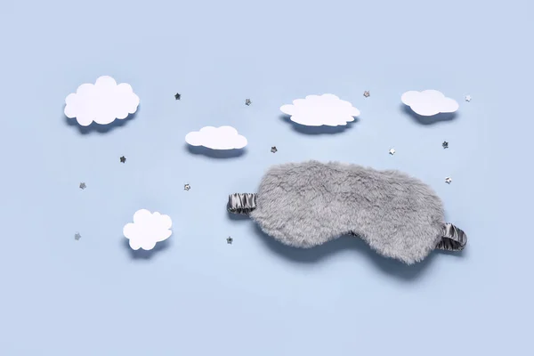 Composition with stylish sleep mask and paper clouds on color background