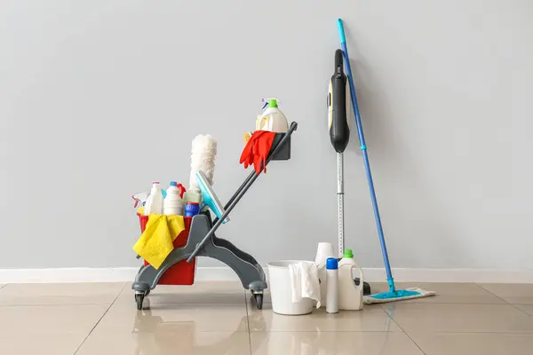 Trolley with cleaning supplies near light wall