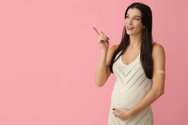ワクチン接種後の若い妊婦は ピンクの背景に何かを指摘する — ストック写真