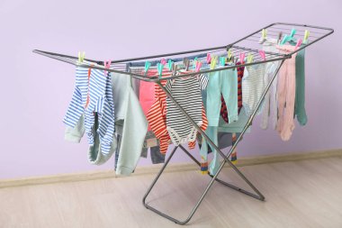 Leylak duvarının yanındaki kurutucuda asılı temiz bebek kıyafetleri.