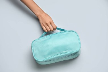 Gri arka planda ilk yardım çantası olan bir kadın el.