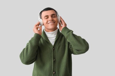 Örgü süveter giyen, kulaklıklı genç bir adam.